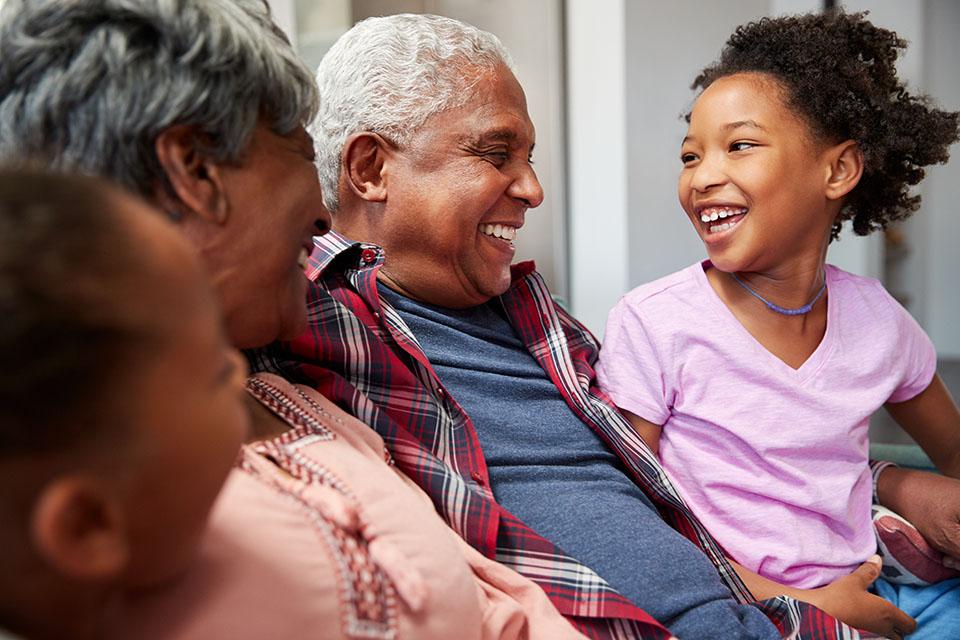 happy child sitting on the couch with grandparents 101 Questions To Ask Grandparents About Their Lives